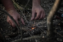 Tech. Sgt. Brett Darby, 5th Operational Support Squadron survival, evade, resistance and escape specialist, shows airmen participating in the combat survival training how to properly start a fire at Garrison, North Dakota, Oct. 9, 2025. Through planning, executing, adapting, and preparing, SERE specialists also help to directly support personnel recovery programs. (U.S. Air Force photo by Senior Airman Alyssa Bankston)