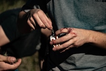 A Team Minot Airman catches a grasshopper during combat survival training at Garrison, North Dakota, Oct. 9, 2025. The course went over basic survival skills including wilderness living, shelter construction, fire building, navigation, first aid, signaling and food and water procurement. (U.S. Air Force photo by Senior Airman Alyssa Bankston)