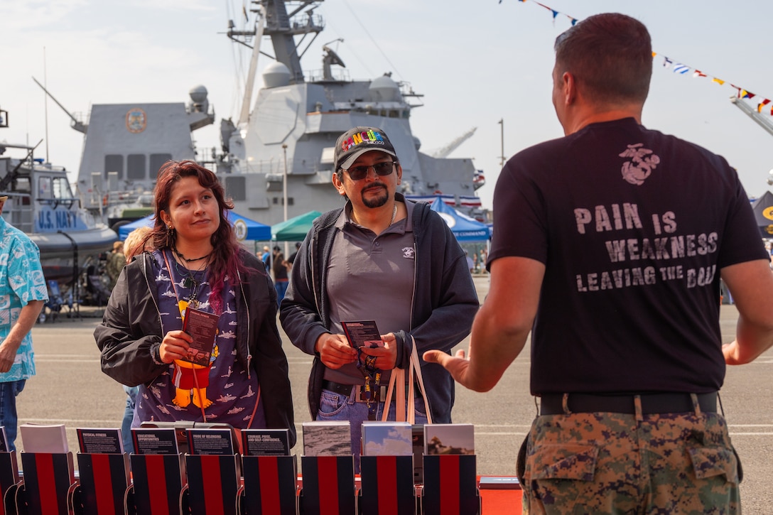 U.S. Marine Corps Sgt. Christian Cone, right, a logistics Marine with Recruiting Station Seattle, interacts with expo attendees at the Fleet Week Expo during Seattle Fleet Week July 31, 2025. Seattle Fleet Week is a time-honored celebration of the sea services and provides an opportunity for the citizens of Washington to meet Sailors, Marines and Coast Guardsmen, as well as witness firsthand the latest capabilities of today's maritime services. (U.S. Marine Corps photo by Sgt. Bruin Largent)