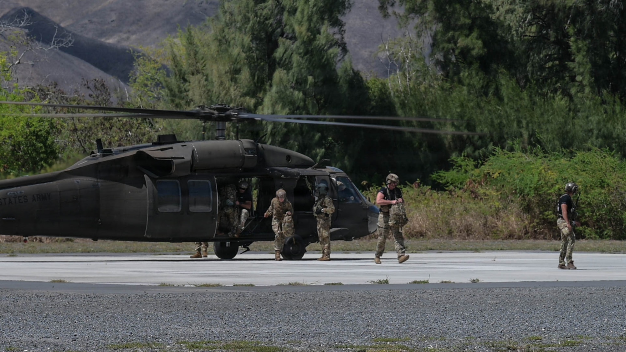 A helicopter land and drops off five personnel.