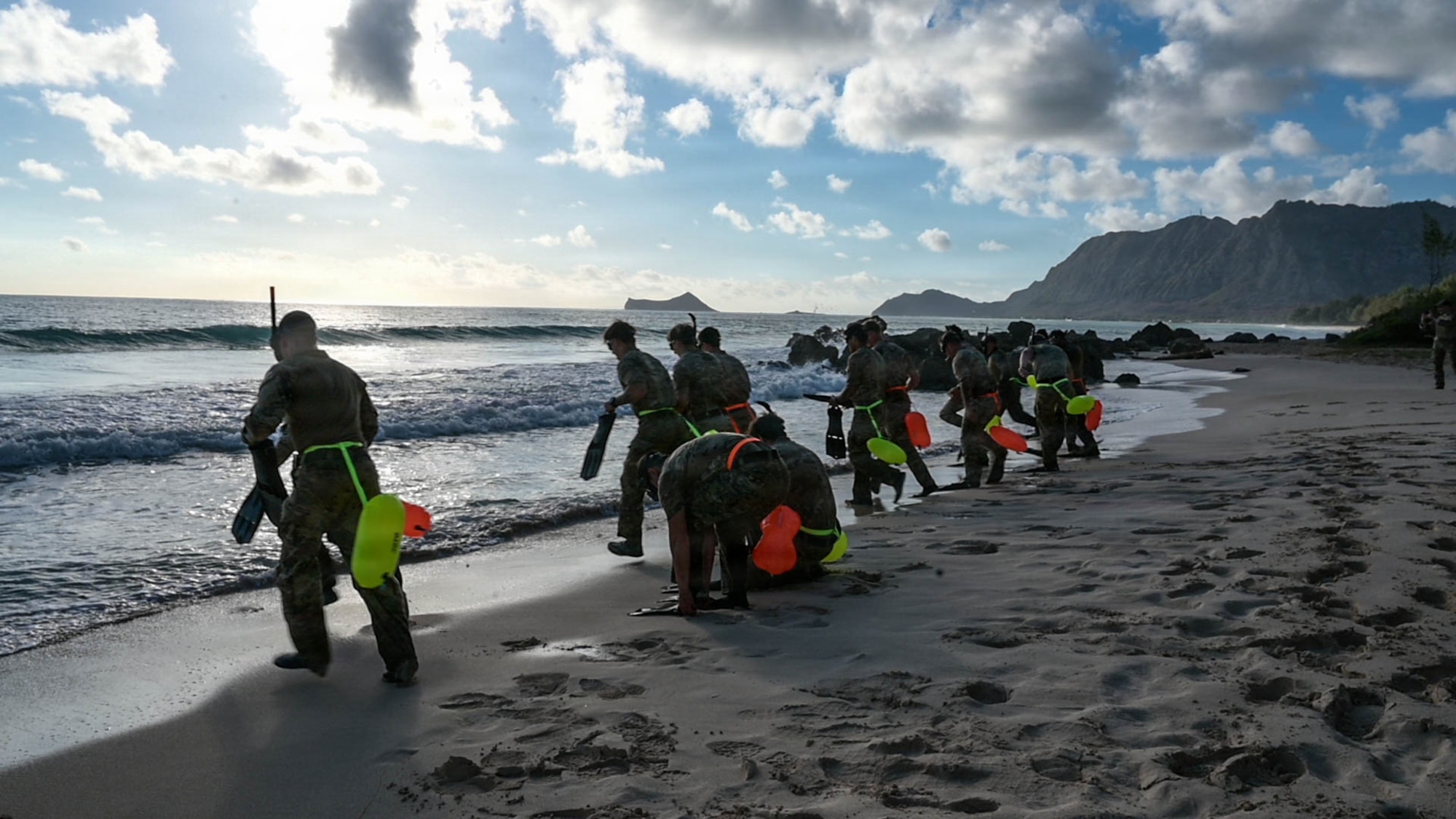 Service members enter the ocean with swim gear for a competition.