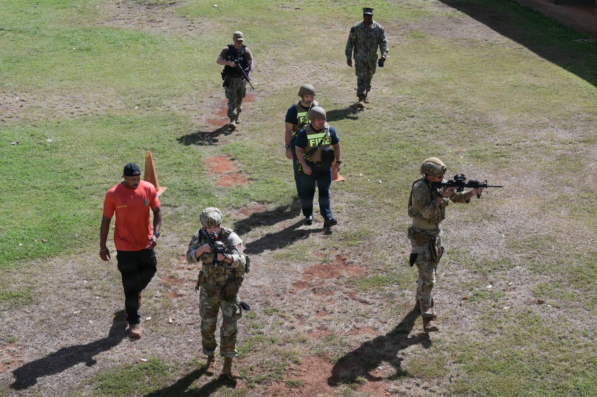 Airmen, Sailors, and firefighters walk in formation during an exercise.