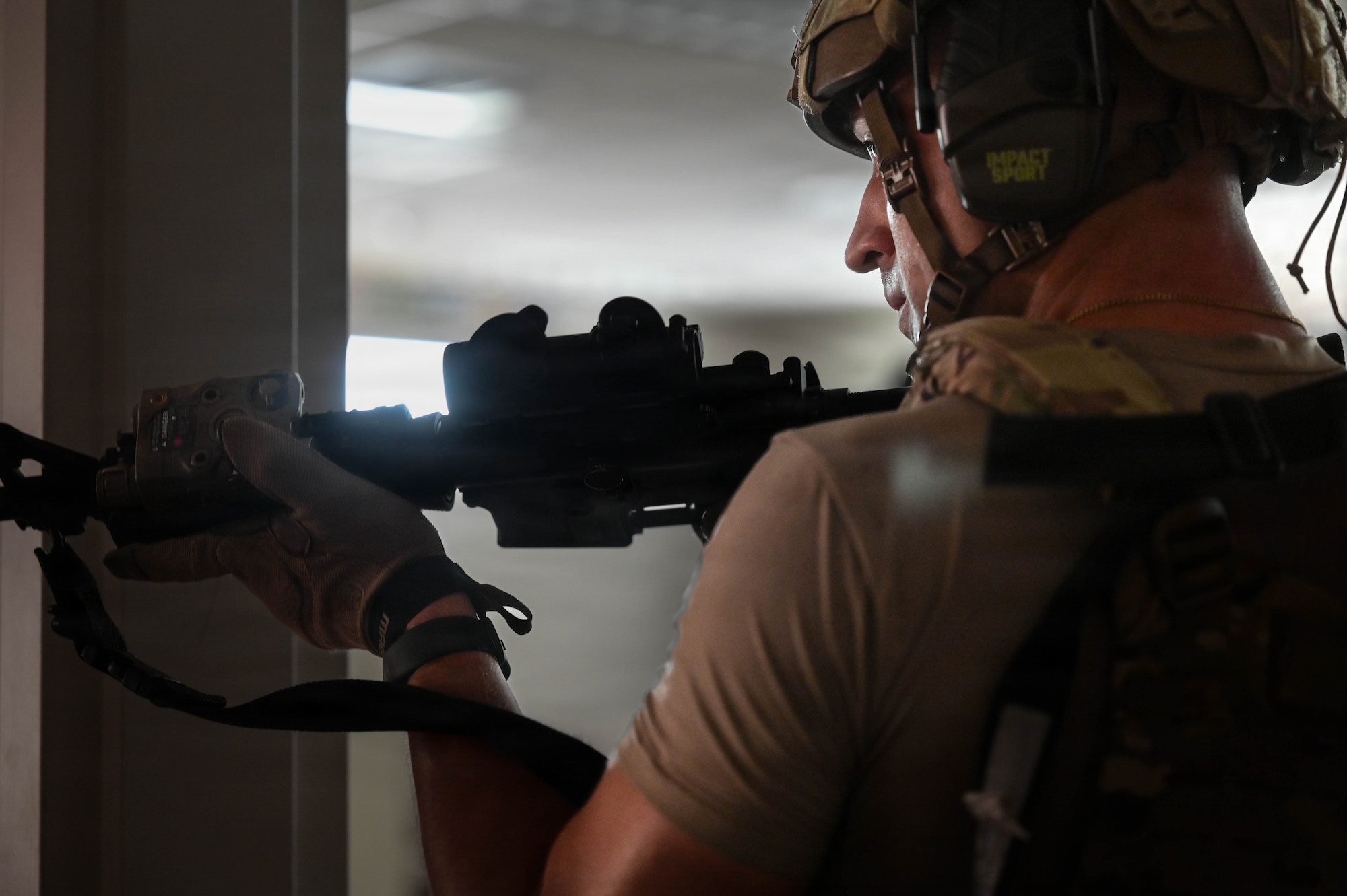 An Airman stands in a doorway with a rifle at the ready position during an exercise.