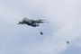 A C-17 aircraft delivers cargo in a drop zone.