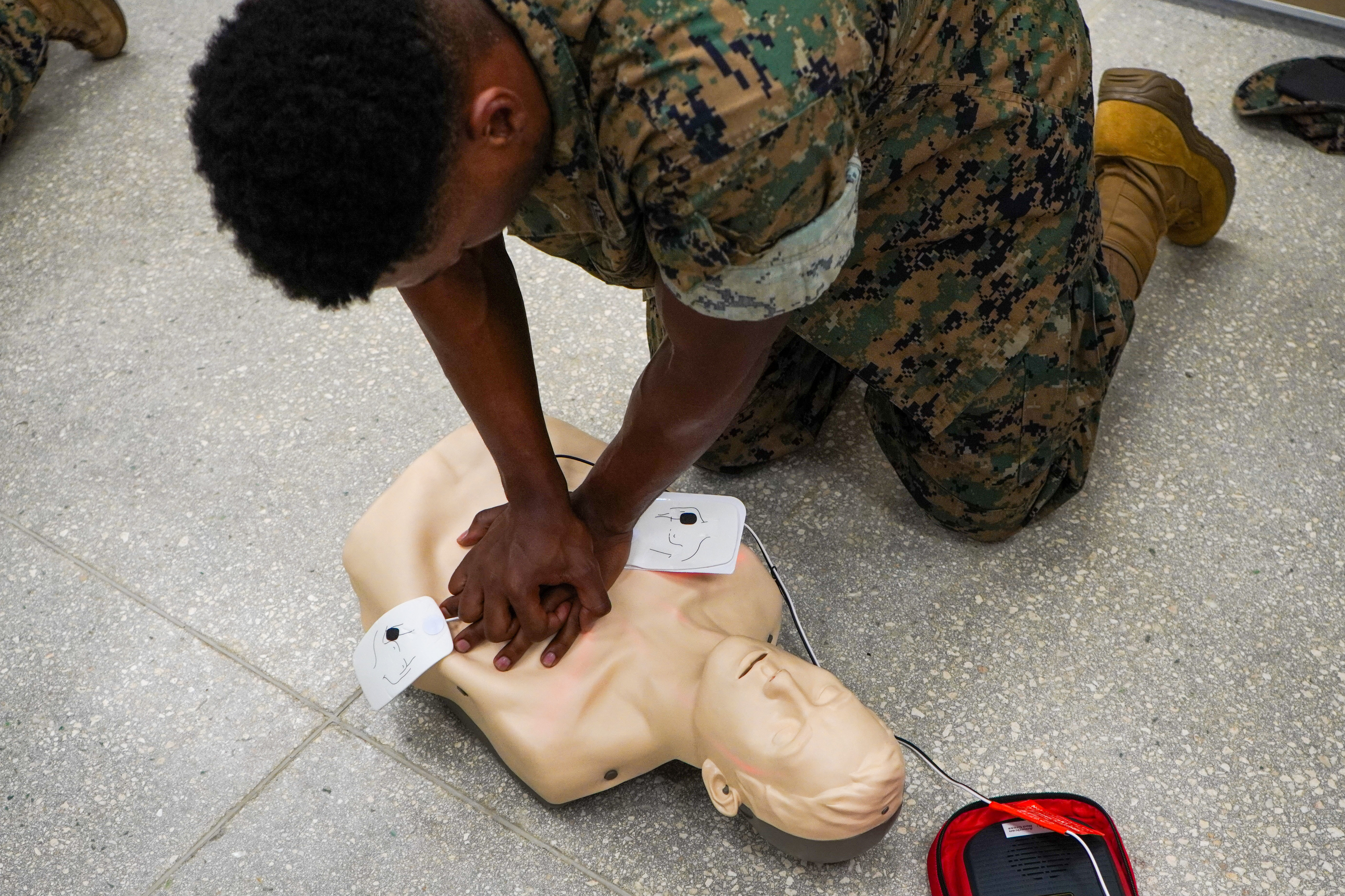 U.S. Marine Corps Sgt. Kendell Jones, personnel non-commissioned officer in charge, Headquarters Company, Marine Corps Base Camp Blaz, performs cardiopulmonary resuscitation on a training dummy with an automated external defibrillator during a CPR and AED course, on MCB Camp Blaz, Guam, Nov. 14, 2025. During the training, Marines learned proper CPR and AED assistance techniques. This allows them to become confident and proficient to respond in emergencies. (U.S. Marine Corps photo by Lance Cpl. Afton Smiley)