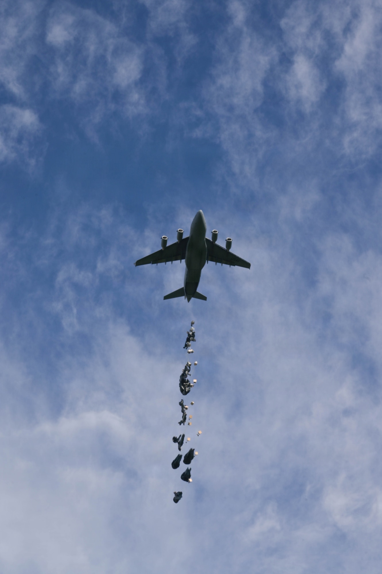 A C-17 aircraft dropping small cargo packages in the air.