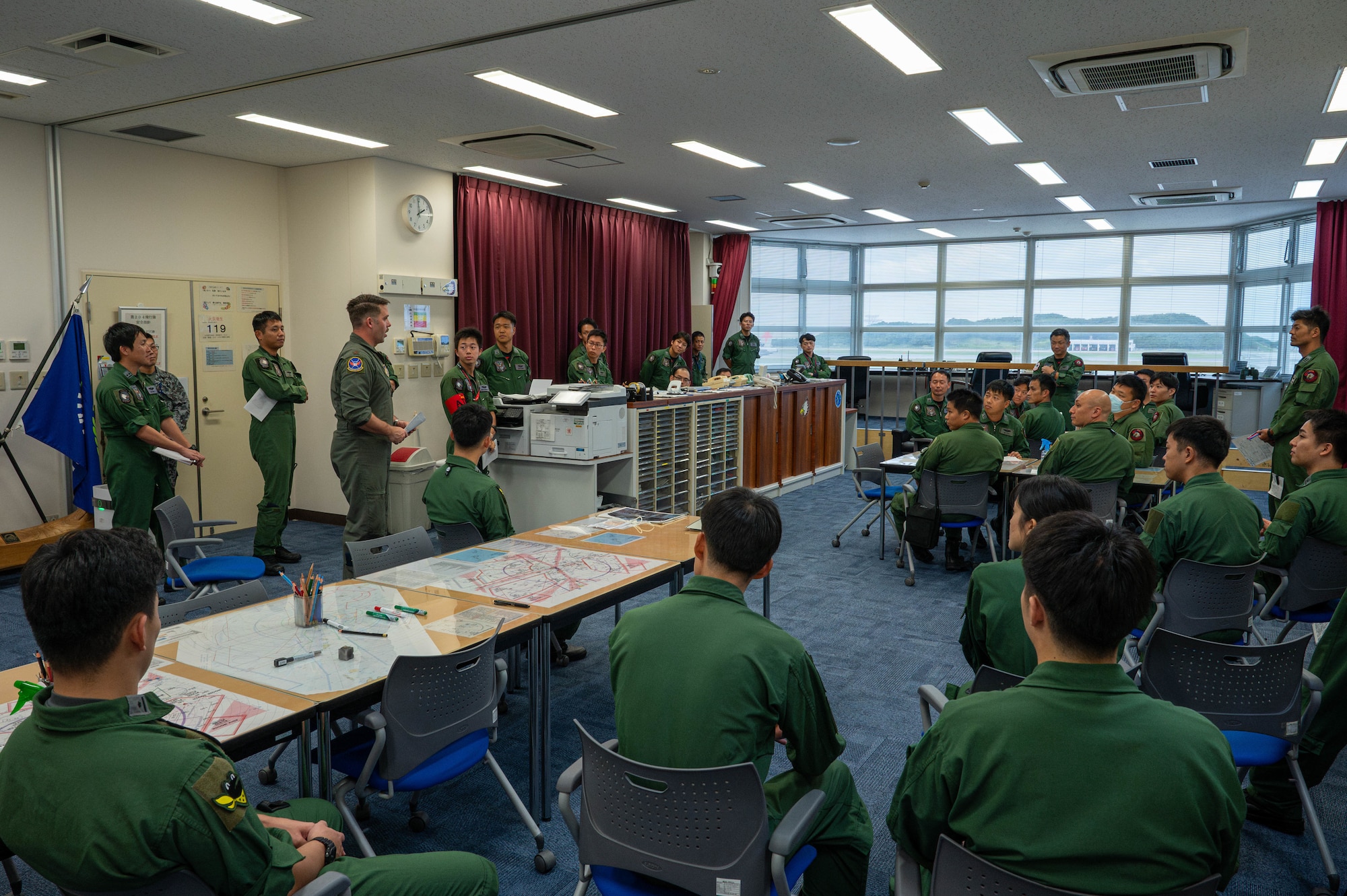 U.S. Air Force Maj. Jesse Ruter, left, weapons systems officer assigned to the 18th Operations Group, speaks with Japan Air Self-Defense Force pilots during a preflight briefing at Naha Air Base, Japan, Nov. 19, 2025. The briefing gave both forces an opportunity to align tactics, procedures and aircrew equipment expectations before the joint operation. (U.S. Air Force photo by Airman Nathaniel Jackson)