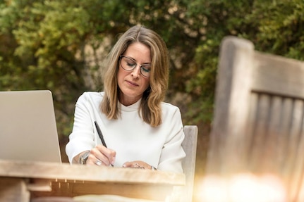 Woman sitting outdoors at table in front of laptop