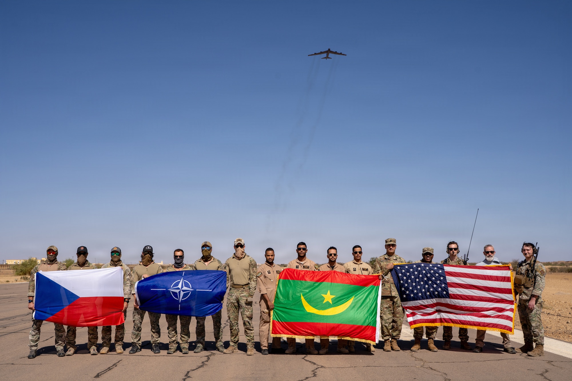 A group of service members with flags next to each other.