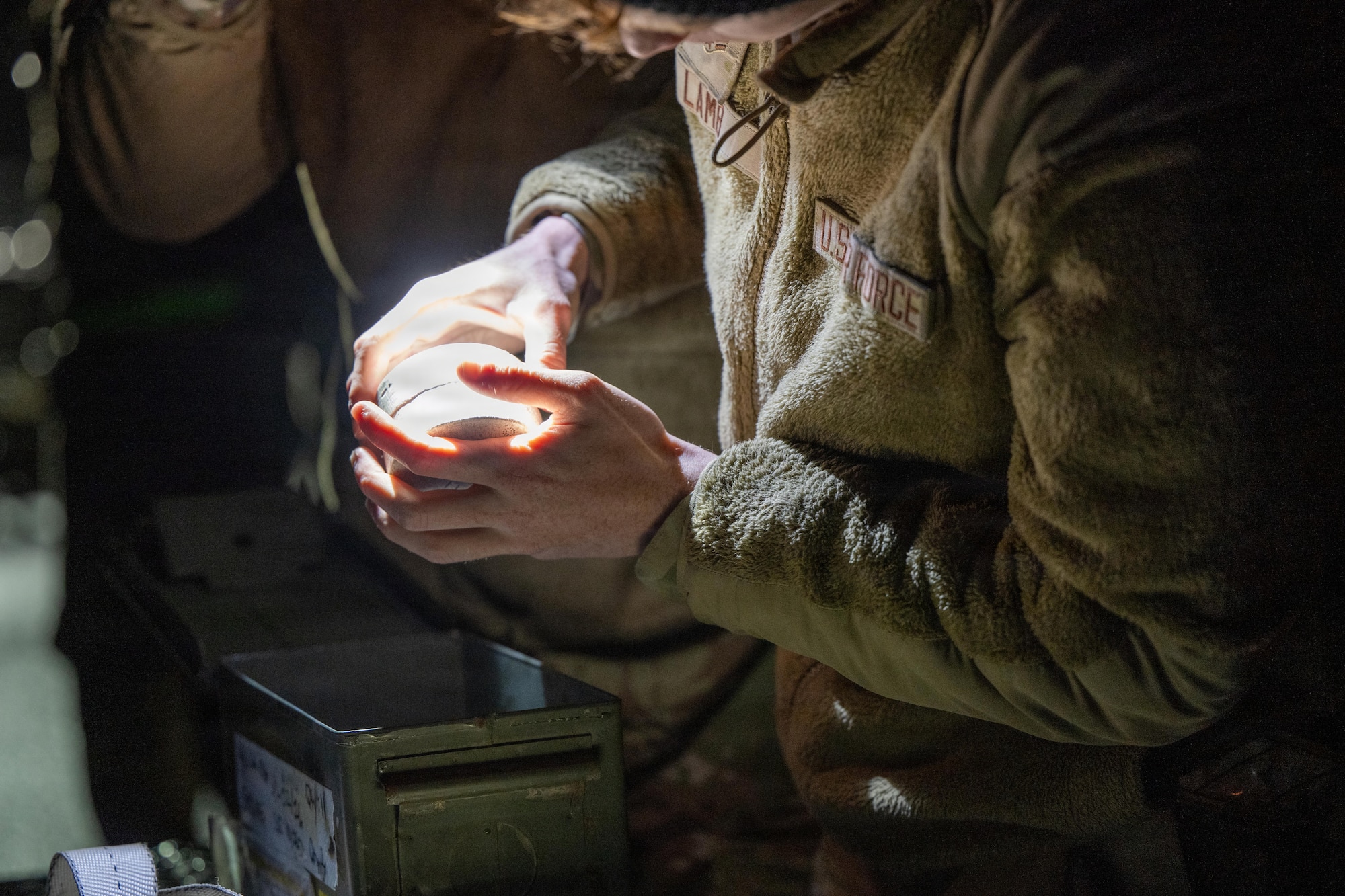 Airmen prepare to load a large weapon onto a B-1 Lancer outside on the flightline