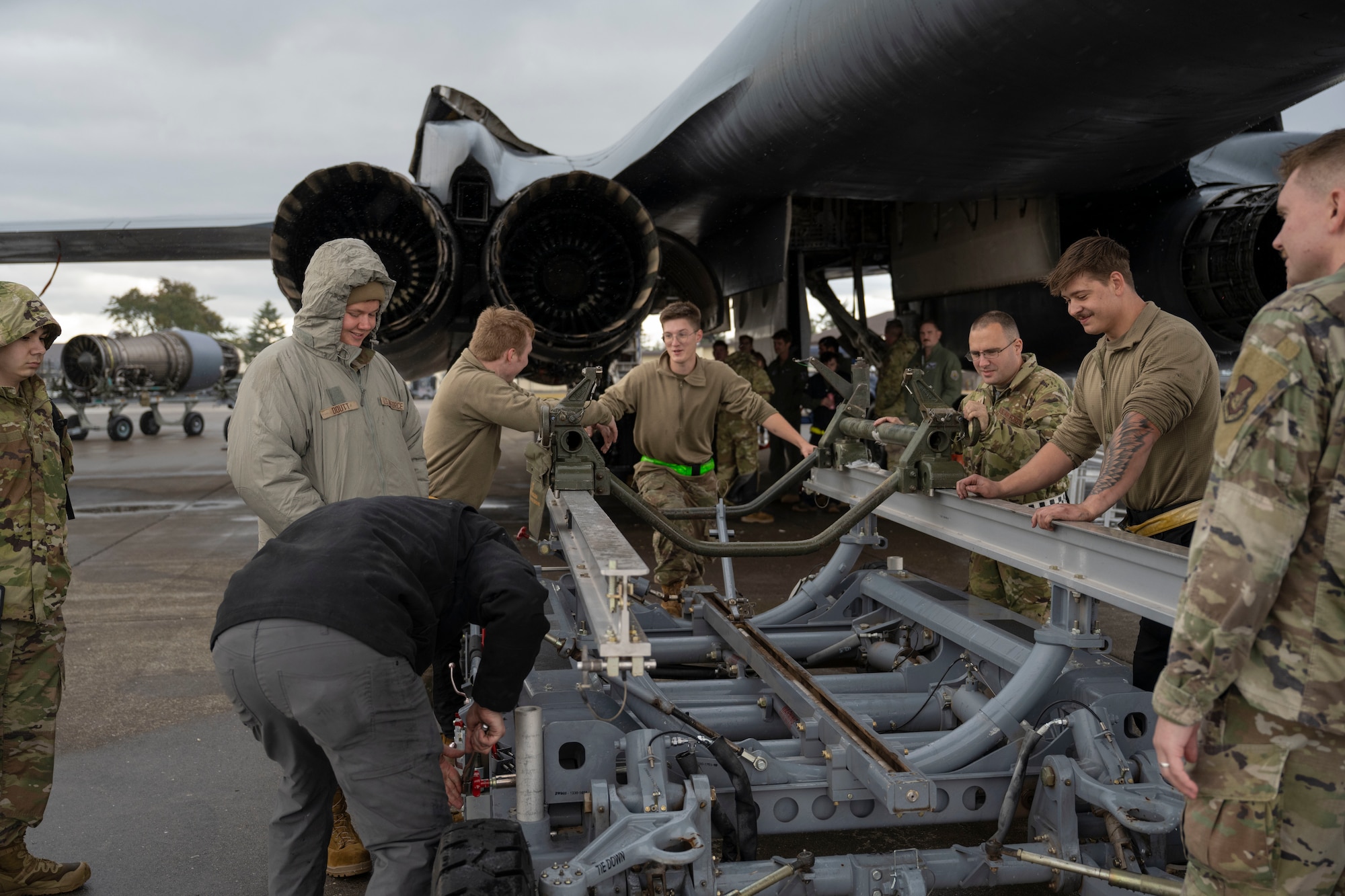 Airmen conduct maintenance on a B-1 Lancer outside in the daylight after raining outside