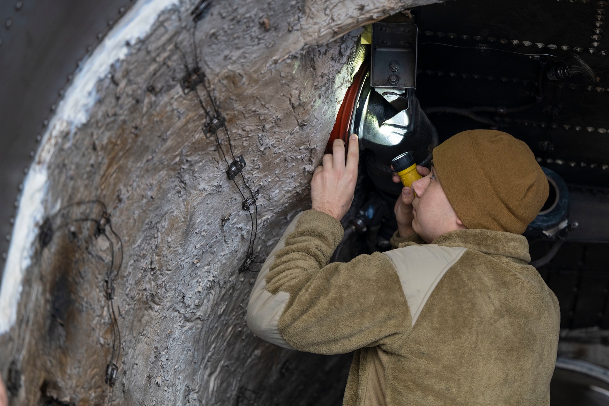Airmen conduct maintenance on a B-1 Lancer outside in the daylight after raining outside