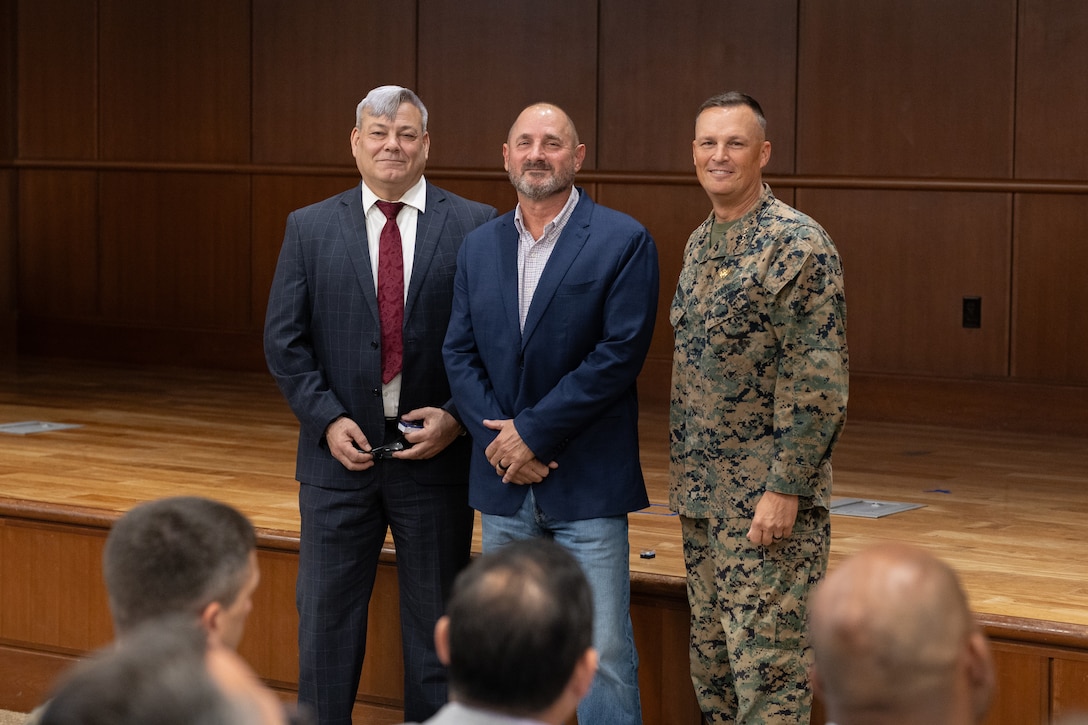 Gregg T. Habel, left, executive director of Marine Force Reserve and Marine Forces South, and U.S. Marine Corps Lt. Gen. Leonard F. Anderson IV, commander of Marine Forces Reserve and Marine Forces South, recognize 25 years of federal service of Dr. Gerald Ormerod (center), MARFORRES and MARFORSOUTH deputy G9 during a town hall meeting at the Marine Corps Support Facility New Orleans, Nov. 20, 2025.  (U.S. Marine Corps photo by Lance Cpl. Carlina Holland)