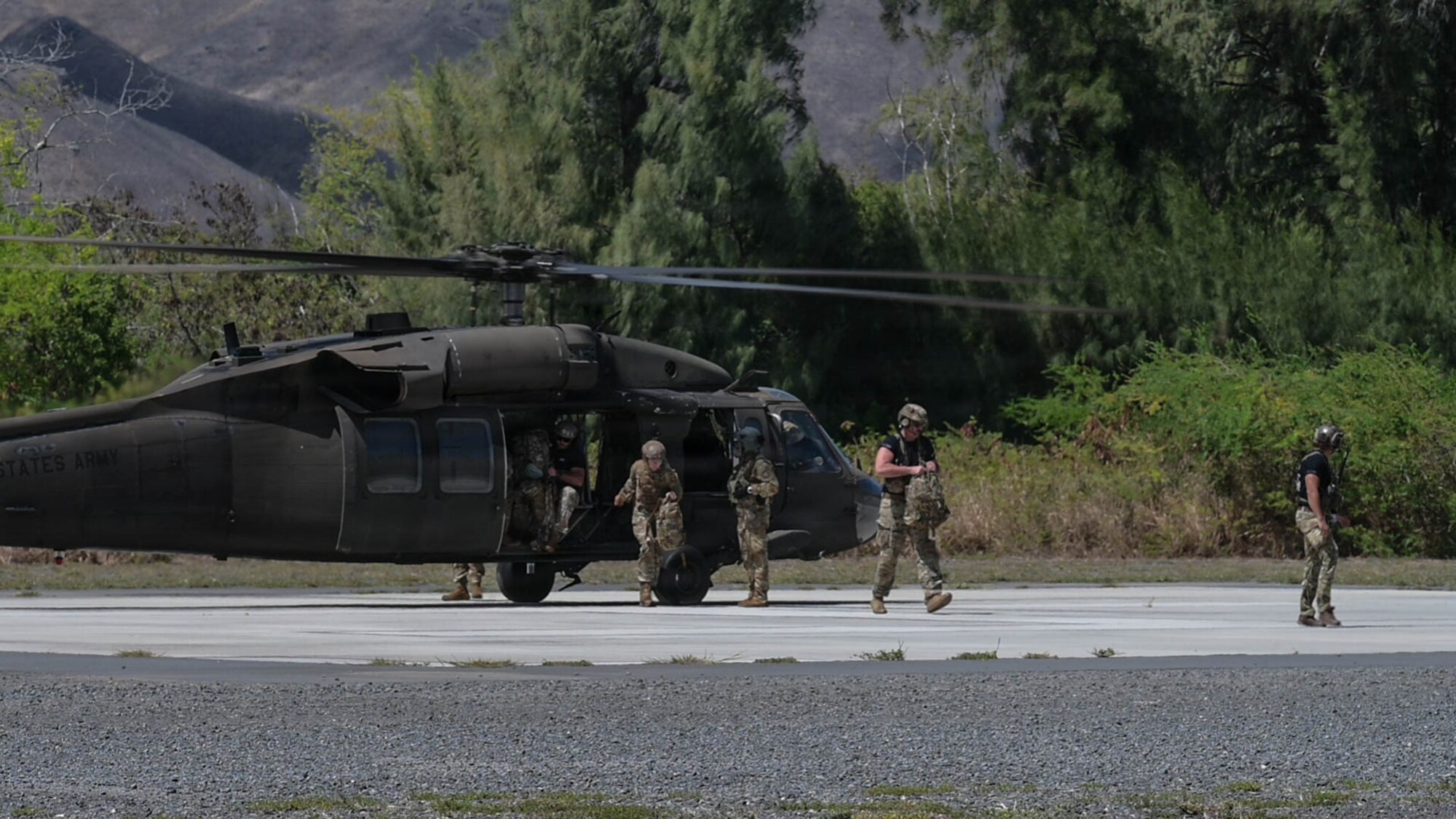 A helicopter land and drops off five personnel.