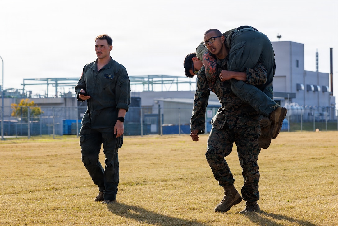 U.S. Marine Corps Cpl. Orion Chamness, an engineer equipment operator for Marine Wing Support Squadron (MWSS) 171, Marine Aircraft Group 12, 1st Marine Aircraft Wing, and a native of Orange Park, Florida, fireman carries his partner during the maneuver under fire portion of the combat fitness test during an Explosive Ordnance Disposal screening test at MCAS Iwakuni, Japan, Nov. 18, 2025. EOD evaluated applicants to laterally move into their military occupational specialty. (U.S. Marine Corps photo by Cpl. Dahkareo Pritchett)