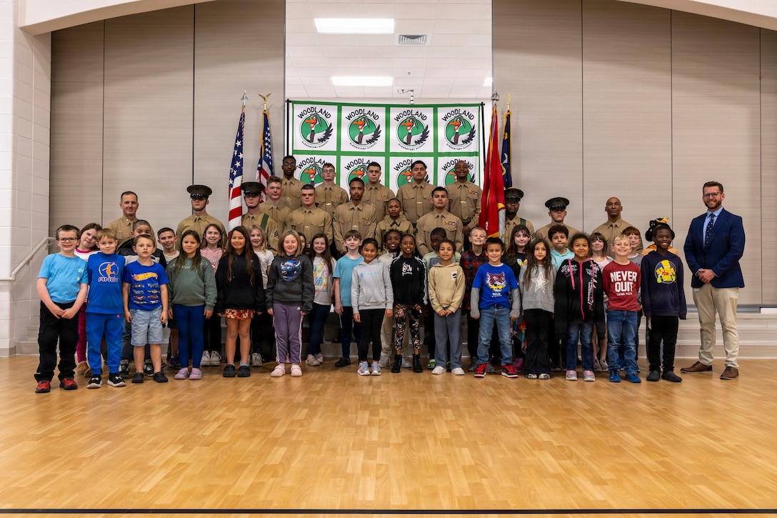 U.S. Marines assigned to II Marine Expeditionary Force Support Battalion pose for a photograph with staff and students at Woodland Elementary School during an Adopt-a-School ceremony at the school in Maysville, North Carolina, Nov. 19, 2025. The Adopt-a-School program is a voluntary program between Woodland Elementary School and II MSB designed to strengthen the connection between the military and local community. (U.S. Marine Corps photo by Sgt. Andrew King)