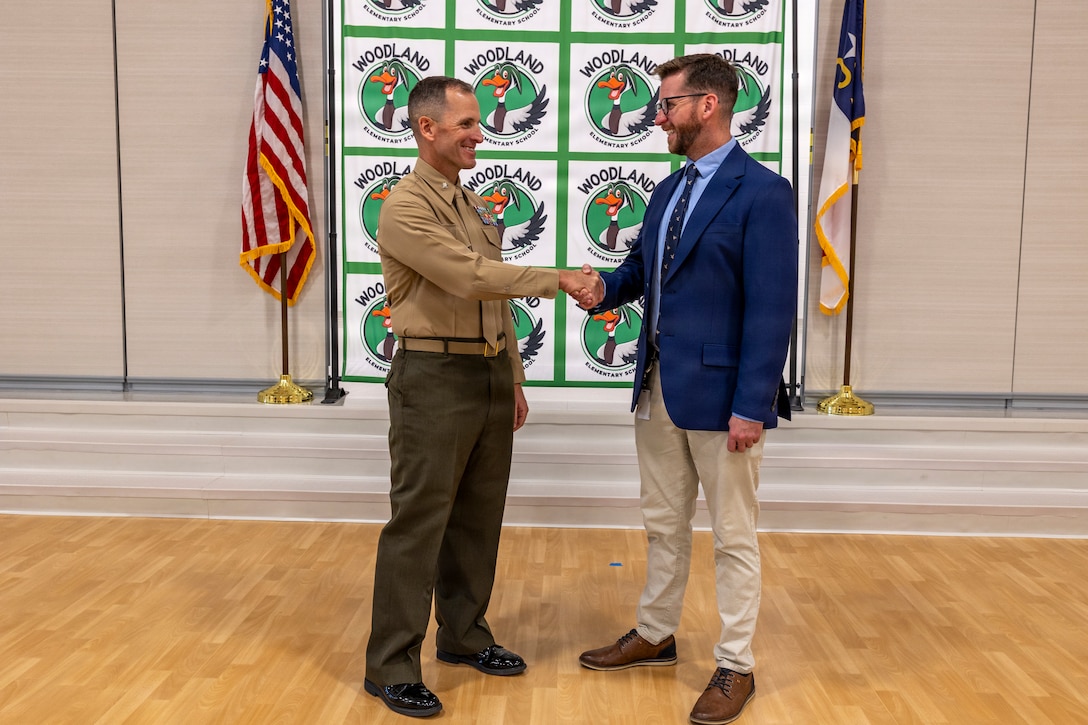 U.S. Marine Corps Lt. Col. Spencer D. Sweet, the commanding officer of II Marine Expeditionary Force Support Battalion, shakes hands with Ryan Reagle, the principal of Woodland Elementary School, during an Adopt-a-School ceremony at the school in Maysville, North Carolina, Nov. 19, 2025. The Adopt-a-School program is a voluntary program between Woodland Elementary School and II MSB designed to strengthen the connection between the military and local community. (U.S. Marine Corps photo by Sgt. Andrew King)