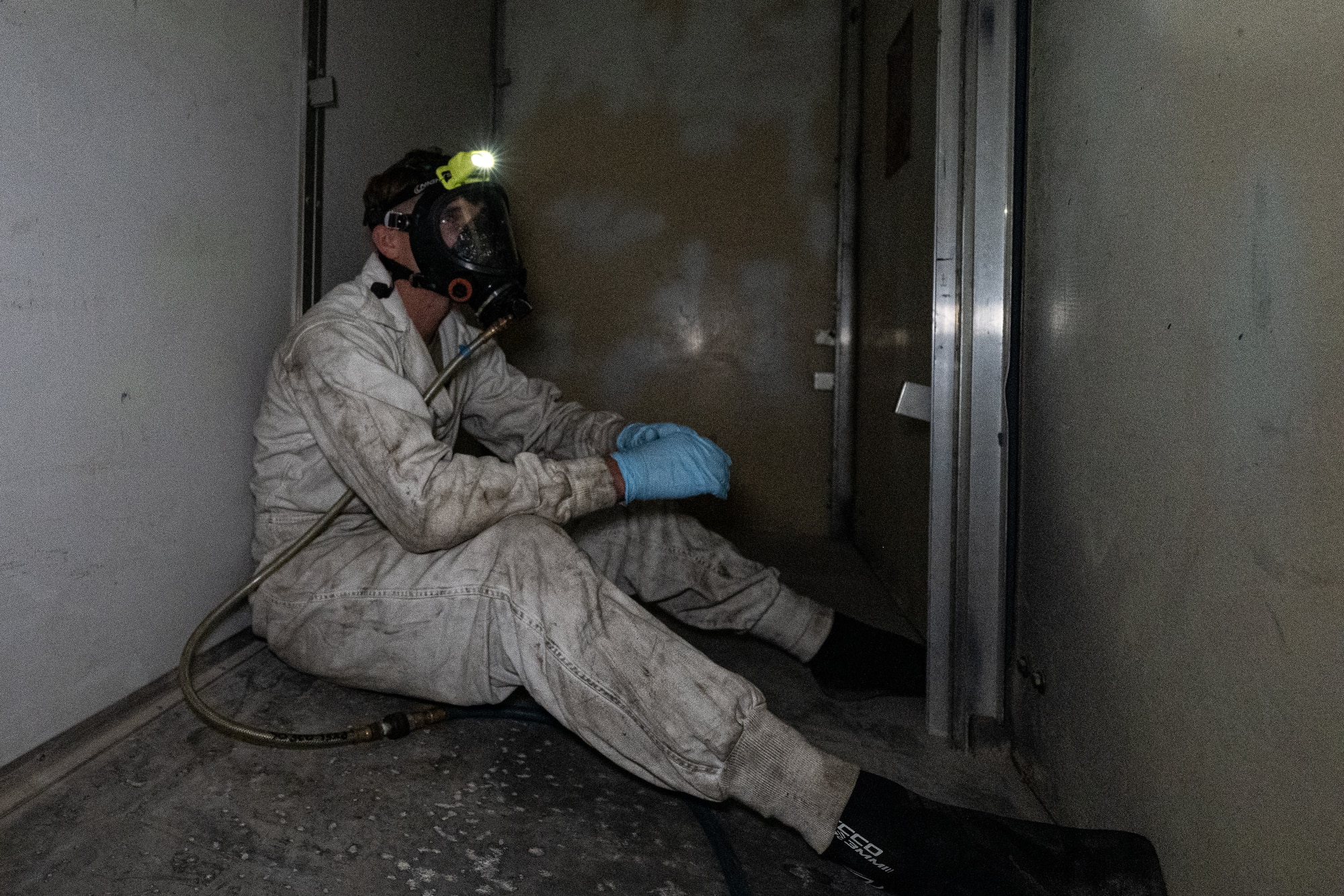 An Airman in a mask sits in a confined space