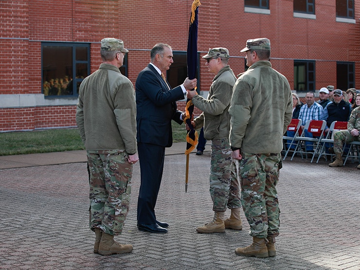 Group of people standing in circle as one passes flag to another