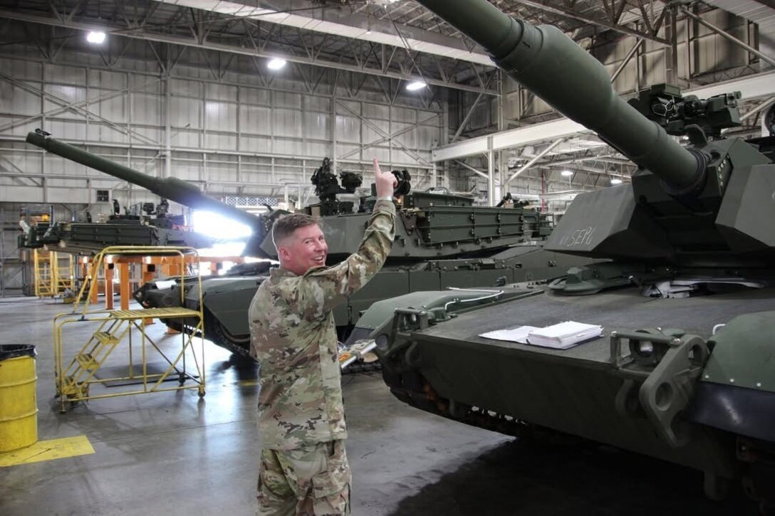 An Army soldier stands with tanks.