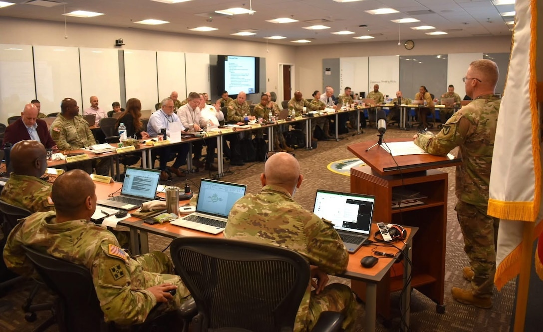Soldiers from the Army Contracting Command sit around a table in a classroom.