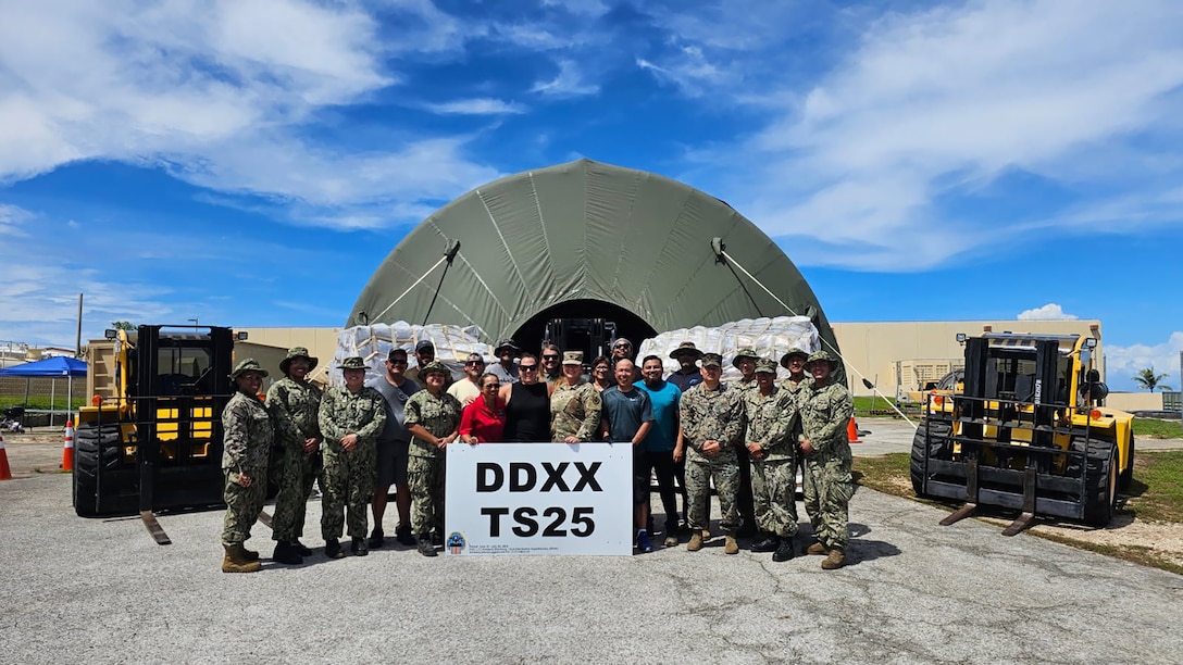 A group of people stand in front of a tent with a sign that says DDXX TS25.