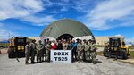 A group of people stand in front of a tent with a sign that says DDXX TS25.