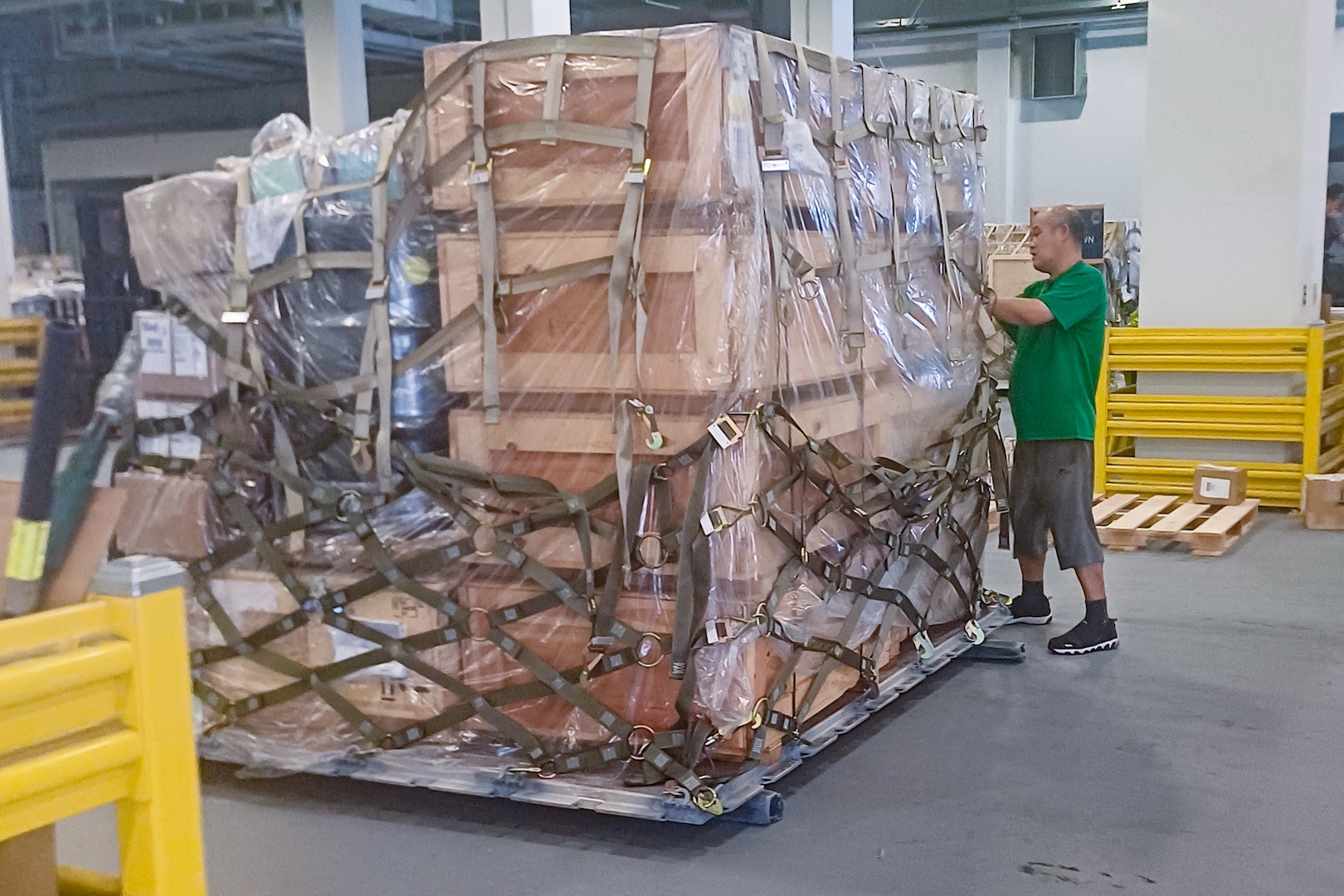 A man stands by a tall stack of crates.