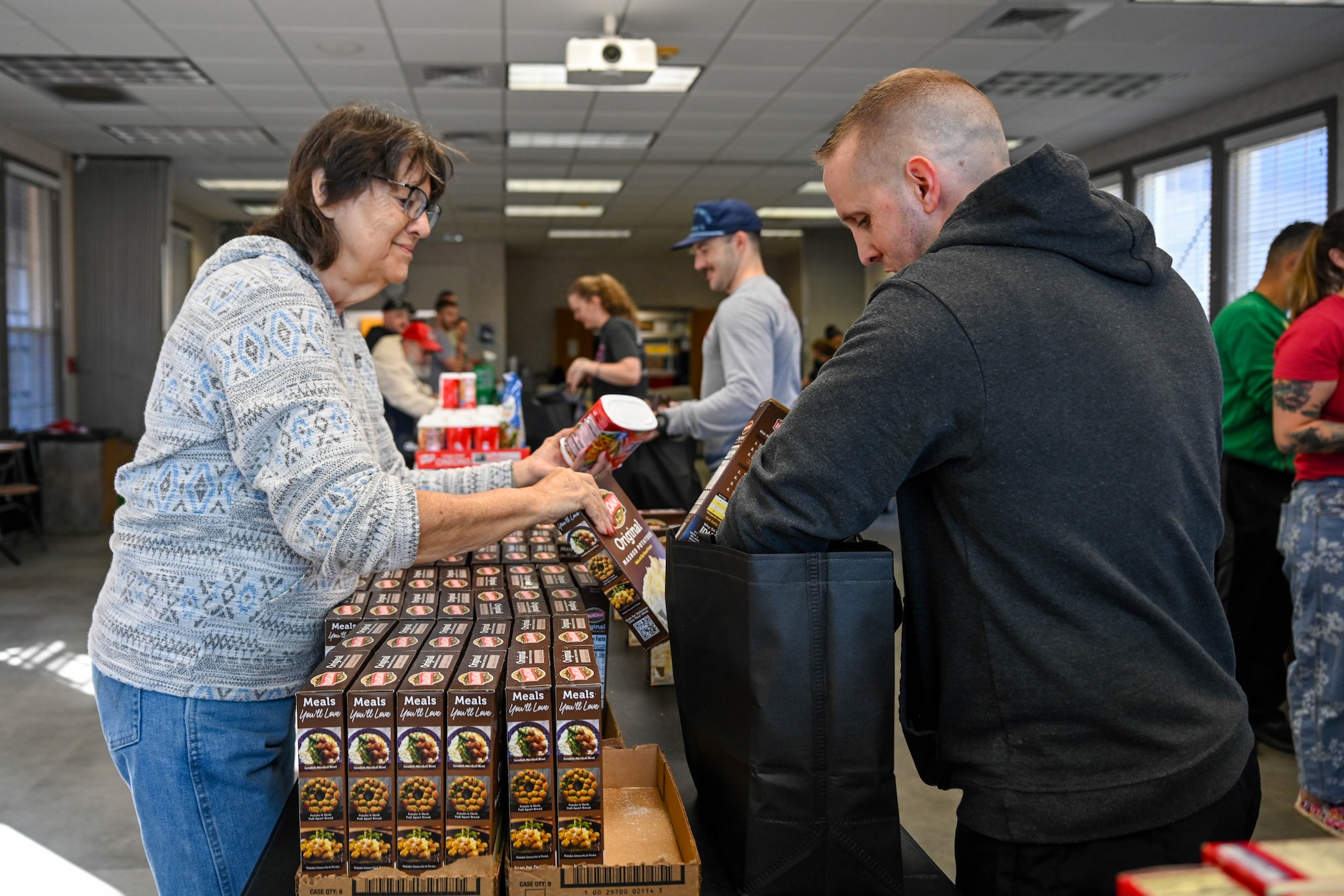People assemble dry goods in a bag.