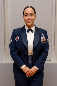 A woman in uniform poses in front of a wall.