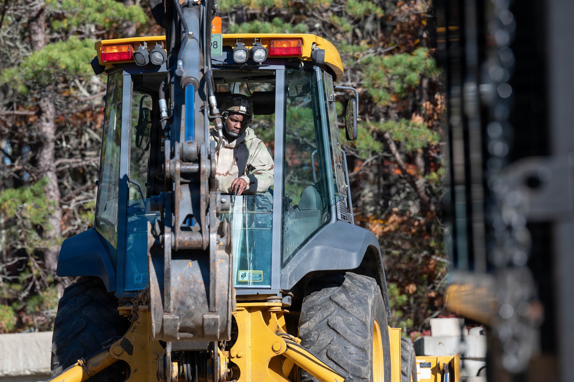 Photo of an Airman operating a backhoe.