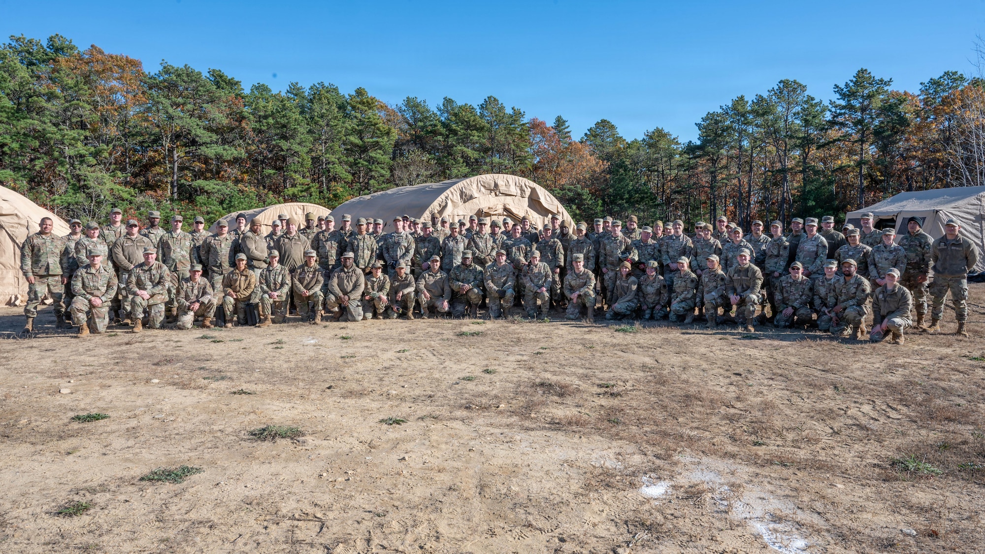 A photo of a large group of Airmen taken outside in front of a tents during an exercise.