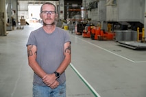 A person poses for a photo in an industrial area.