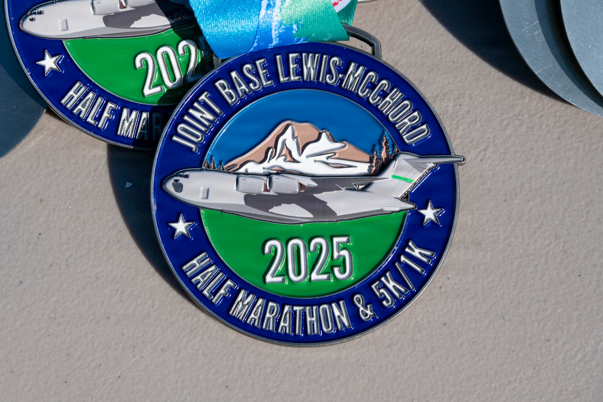 a medallion with a C-17 Globemaster III on it that says "Joint Base Lewis-McChord 2025 Half Marathon and 5K/1K"