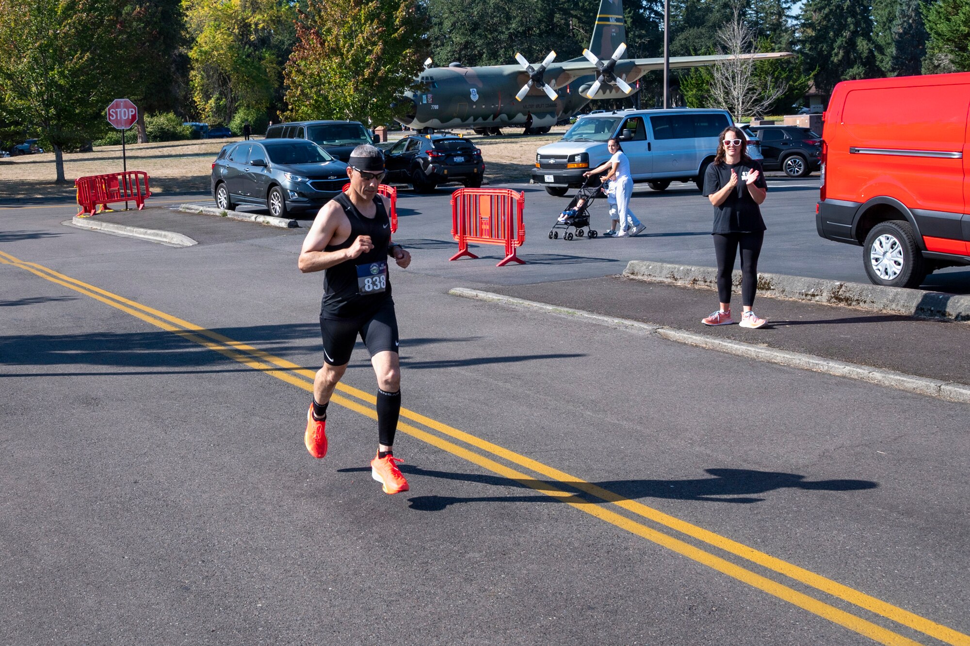 a man runs mid jog on a street with an aircraft in the background