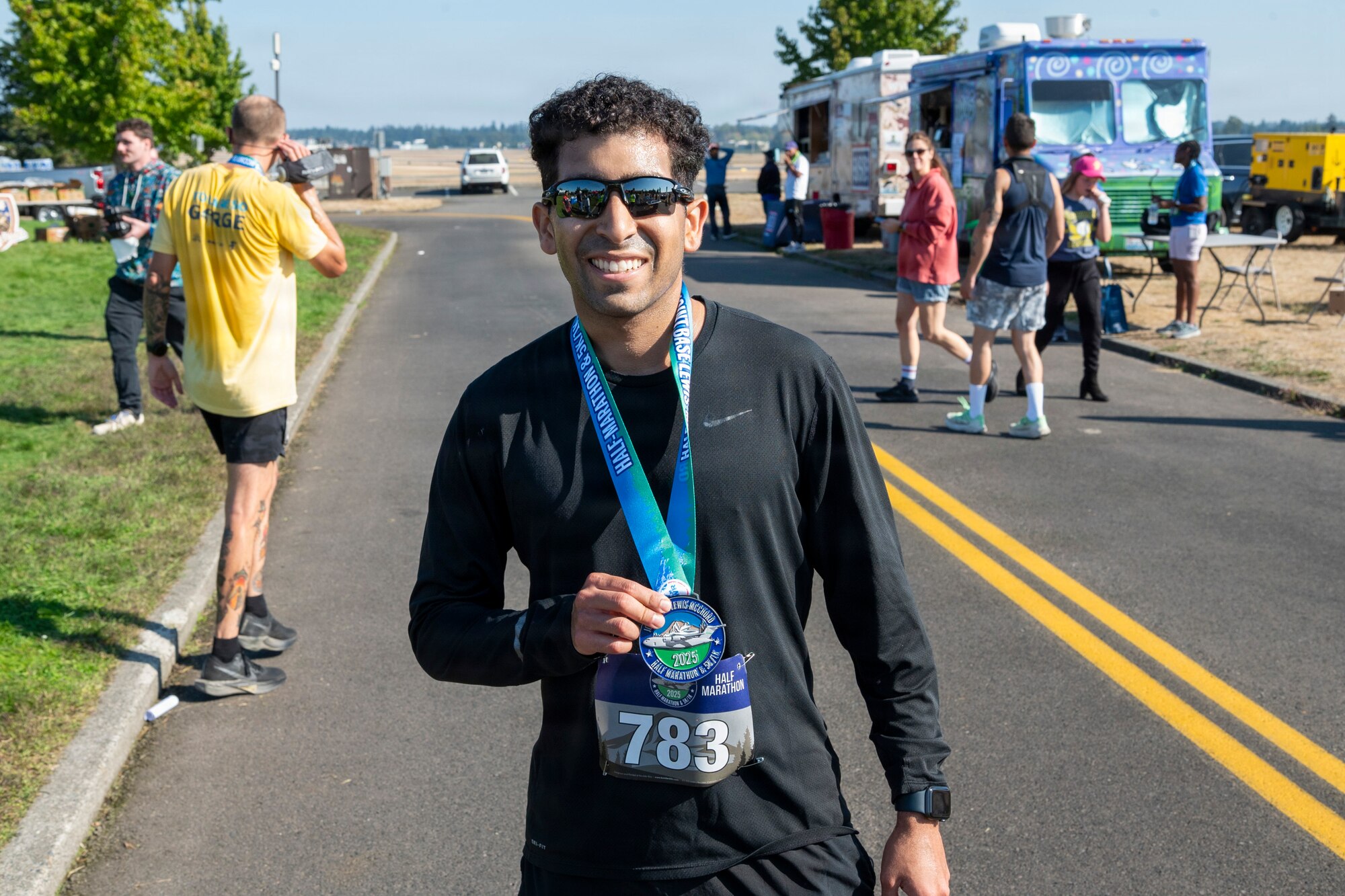 a man in sunglasses holds up a medal and smiles