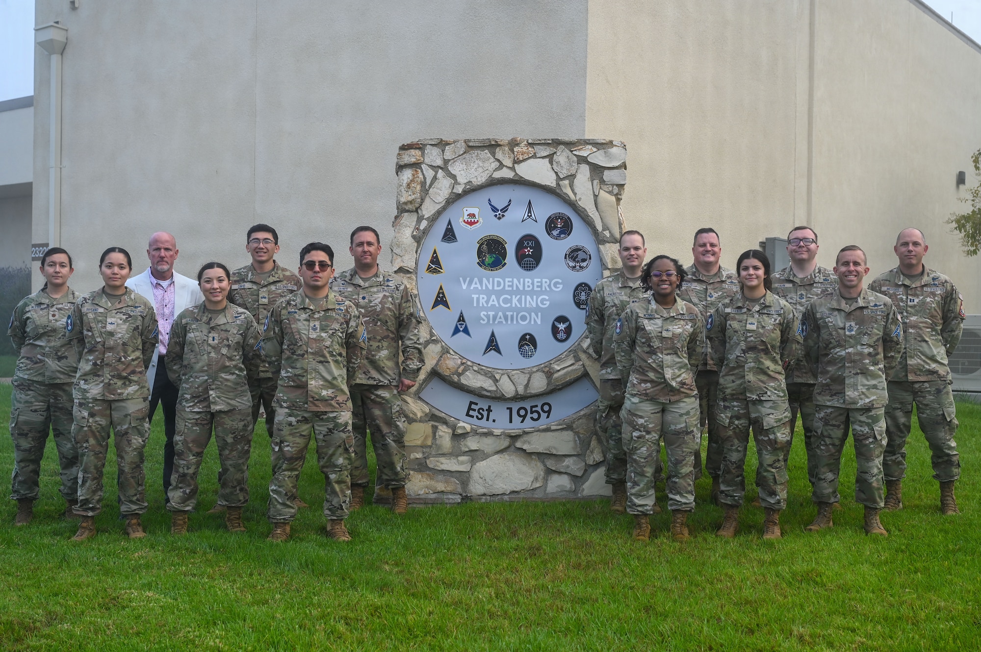 a group of people stand on lawn near a sign