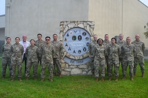a group of people stand on lawn near a sign