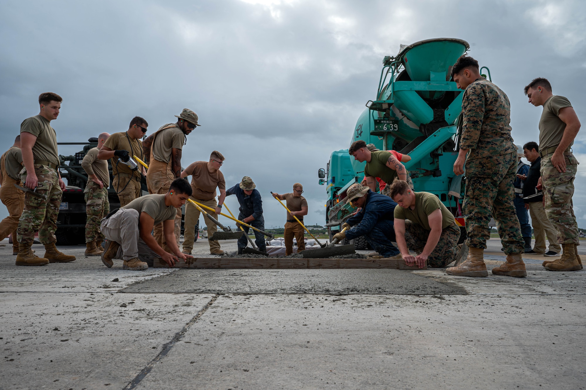 U.S. military service members assigned to Kadena Air Base place and level concrete as part of full-depth pavement repair on a runway at Kadena Air Base, Nov. 14, 2025. The 18th Civil Engineer Group is the largest civil engineer unit in the Air Force, being composed of two squadrons: 18th CES and 718th CES. (U.S. Air Force photo by Airman Nathaniel Jackson)