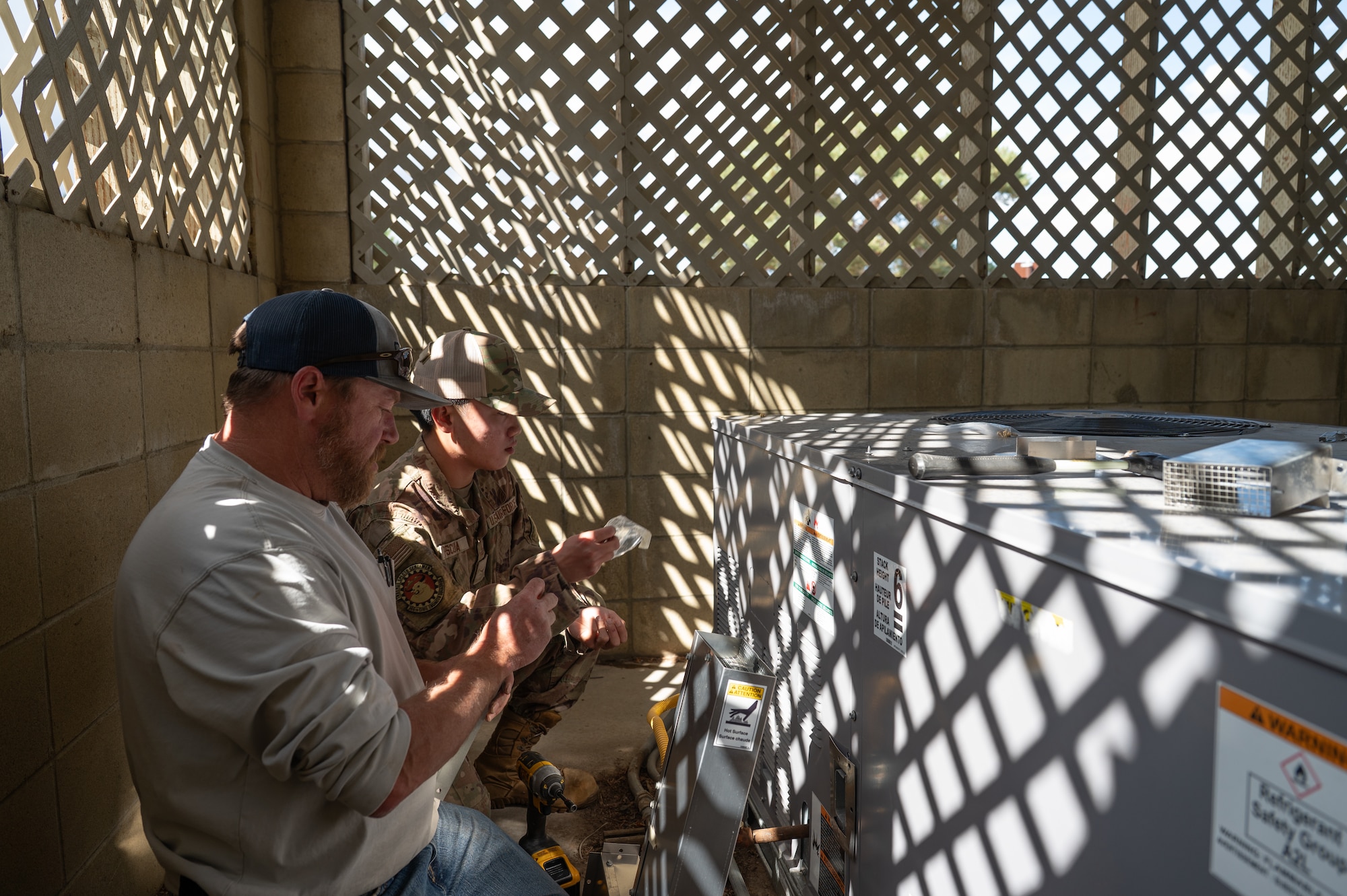 Service members work on HVAC unit