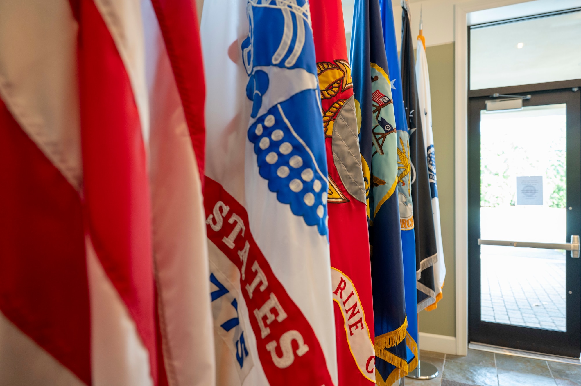 A series of flags stand on display inside the Center for Families of the Fallen, Dover Air Force Base, Delaware, Nov. 18, 2025. The 6,339 square foot renovated facility includes segregated areas and rooms for families to use for privacy and separation, a cafe area with snacks and beverages, a meditation room, baby changing stations in both restrooms, a private nursing area in the women's restroom, a children's activity room with a chalkboard wall, games and toys and a separate area with TVs and gaming systems. (U.S. Air Force photo by Staff Sgt. Frank Rohrig)