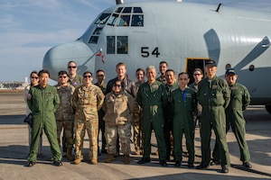 Japan Maritime Self-Defense Force members and U.S. Air Force Airmen pose for a photo in front of an aircraft.