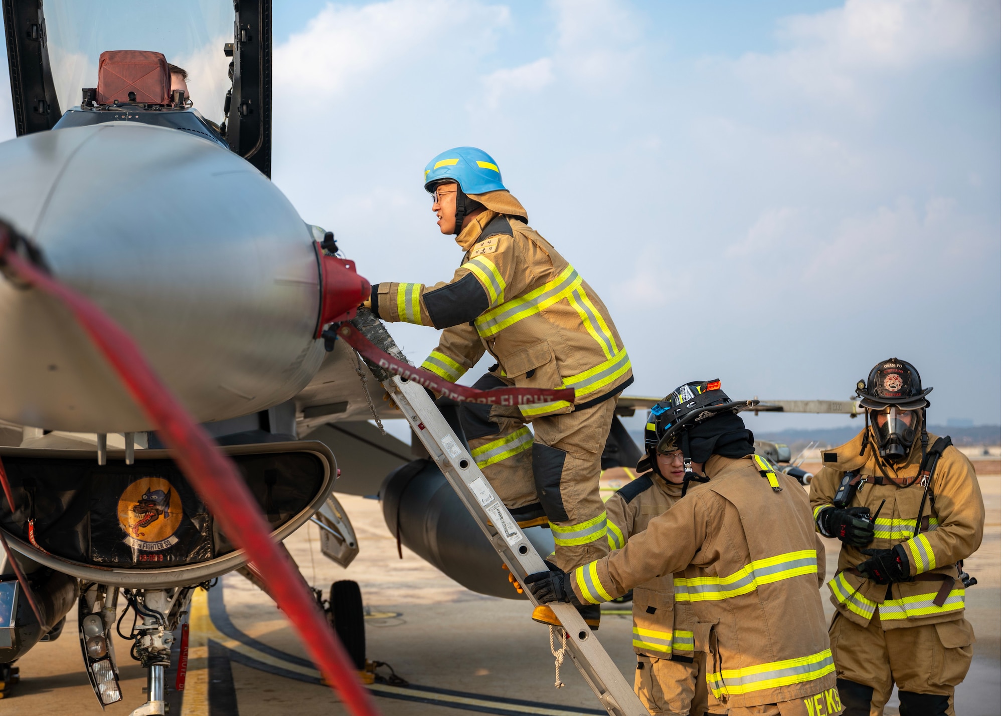 A Republic of Korea Air Force firefighter climbs a ladder during a pilot egress training at Osan Air Base, ROK, Nov. 20, 2025.  U.S. and ROKAF firefighters participated in a series of events including an equipment display, mission brief, fire station tour, joint physical training, an F-16 Fighting Falcon pilot rescue exercise, and a 1410 hose deployment drill. (U.S. Air Force photo by Staff Sgt. Sarah Williams)