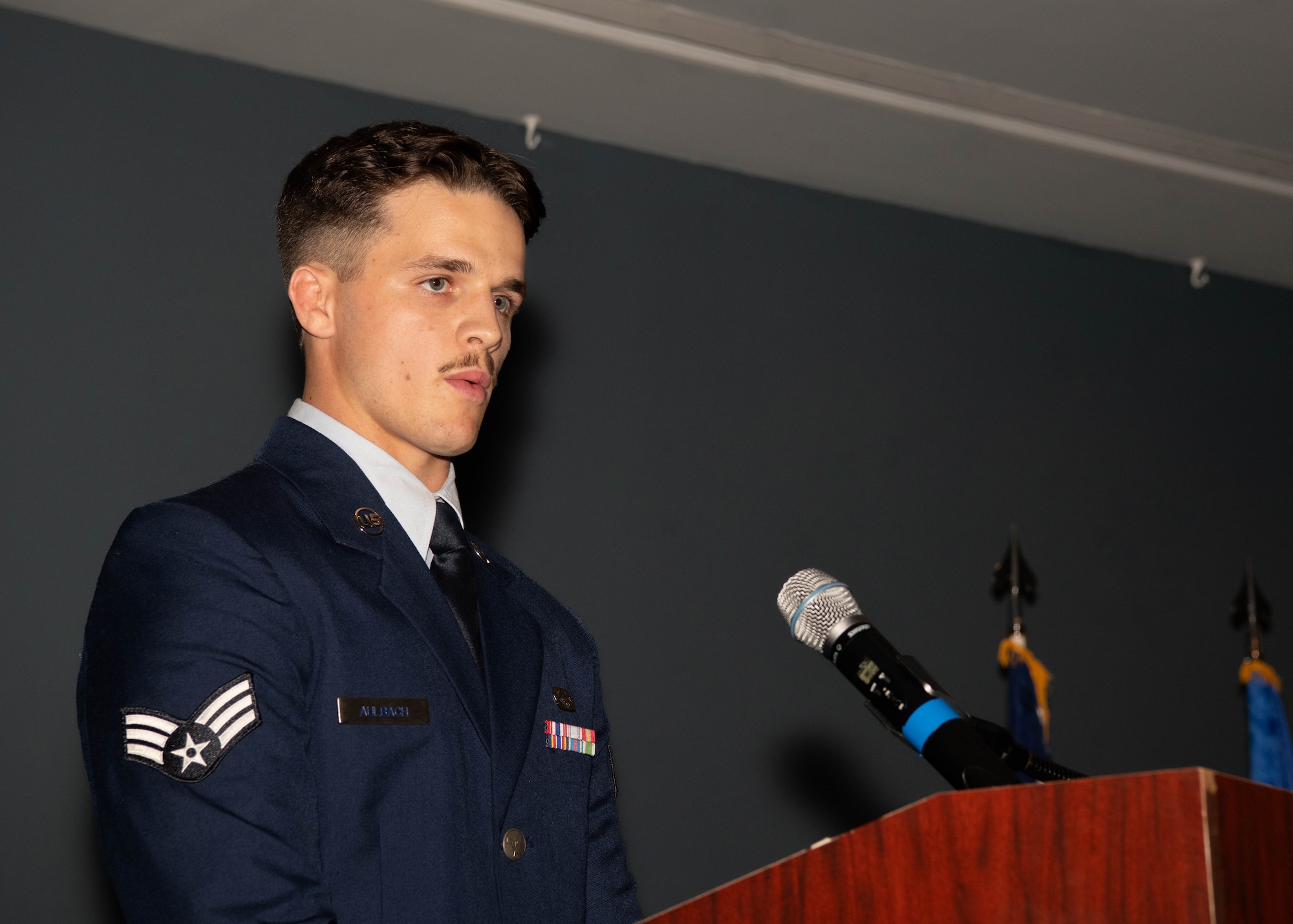 A photo of an Airman delivering a speech on stage.