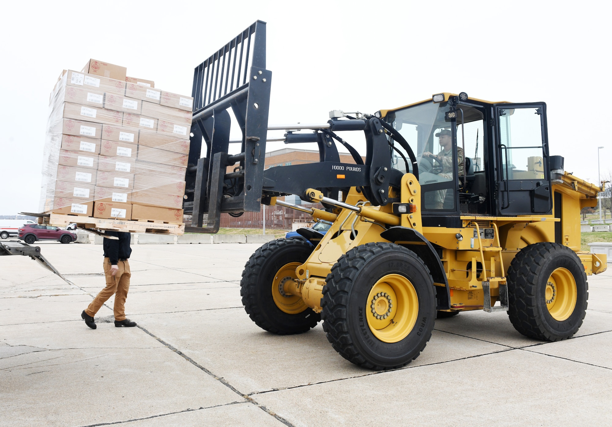Airmen drives a forklift carrying boxes of food