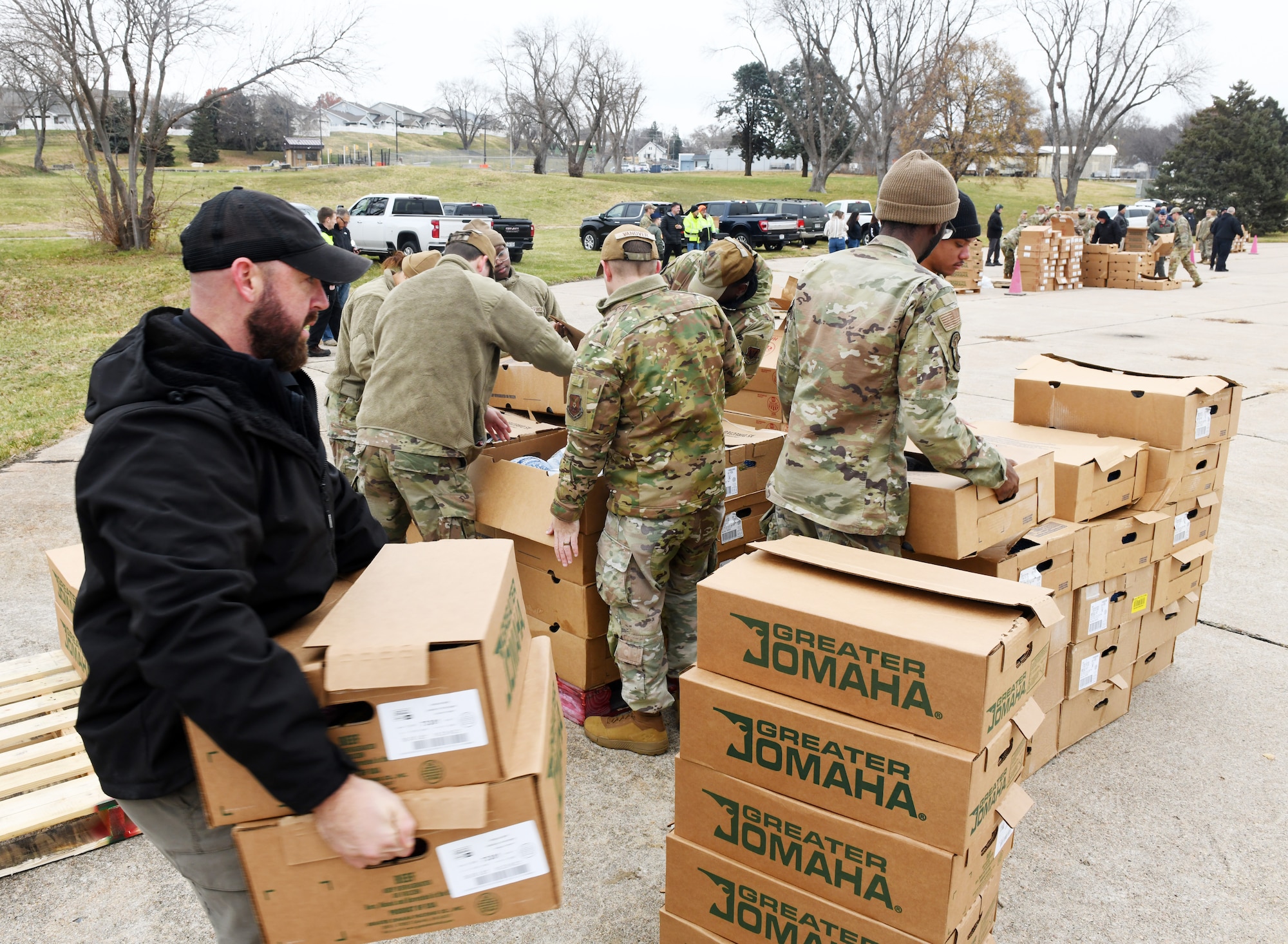 Uniformed military members stacking boxes in a parking lot.