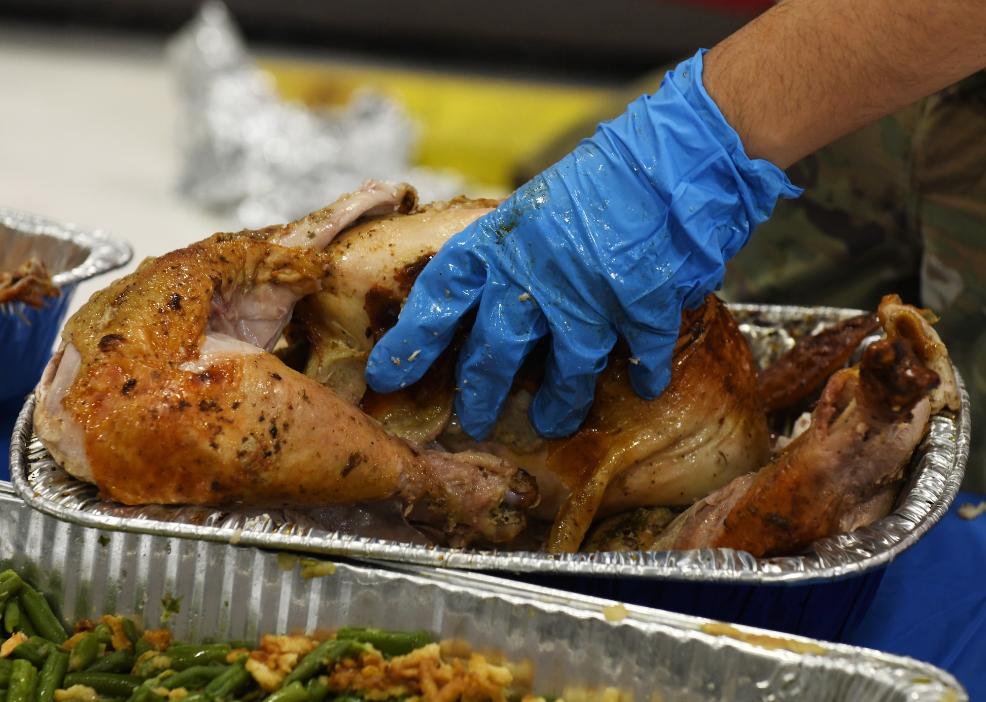 hands with blue rubber gloves carves turkey