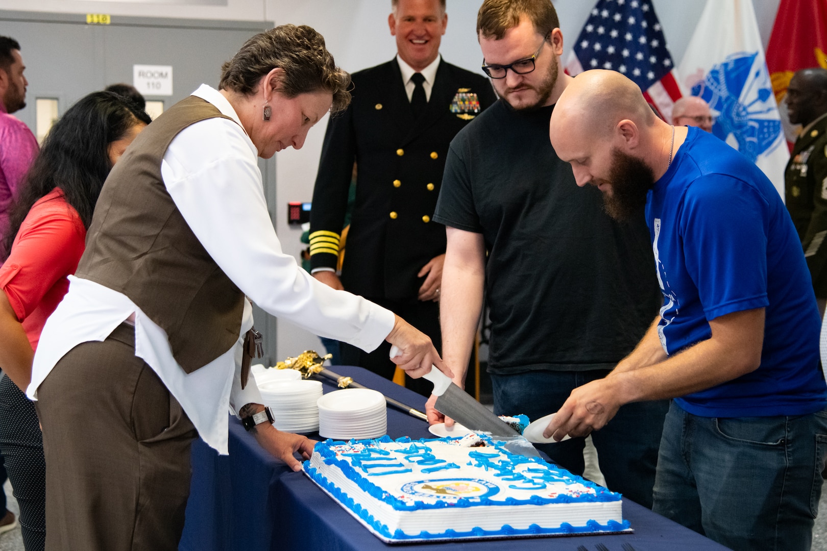A group of people wait in line to get a piece of cake.
