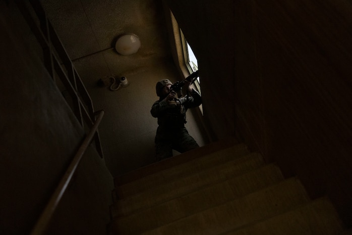 U.S. Marine Corps Cpl. Dylan Daniel, a motor vehicle operator with Combat Logistics Battalion 2, Combat Logistics Regiment 2, 2nd Marine Logistics Group, posts security through a window at the Infantry Immersion Trainer at Marine Corps Base Camp Lejeune, North Carolina, Nov. 21, 2025. The IIT is a facility which provides an urban training environment for Marines and Sailors, aiding in increasing combat efficiency by training in realistic conditions. Daniel is a native of Illinois. (U.S. Marine Corps photo by Lance Cpl. Isabella Ramos)