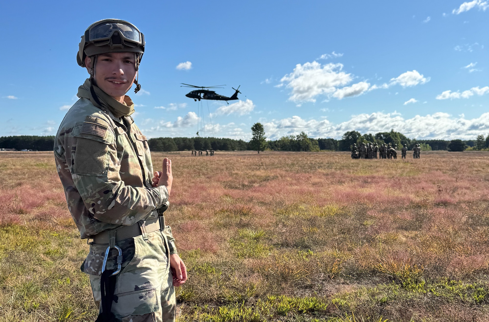 Garcia stand in a field pointing to a sling operation happening behind him.